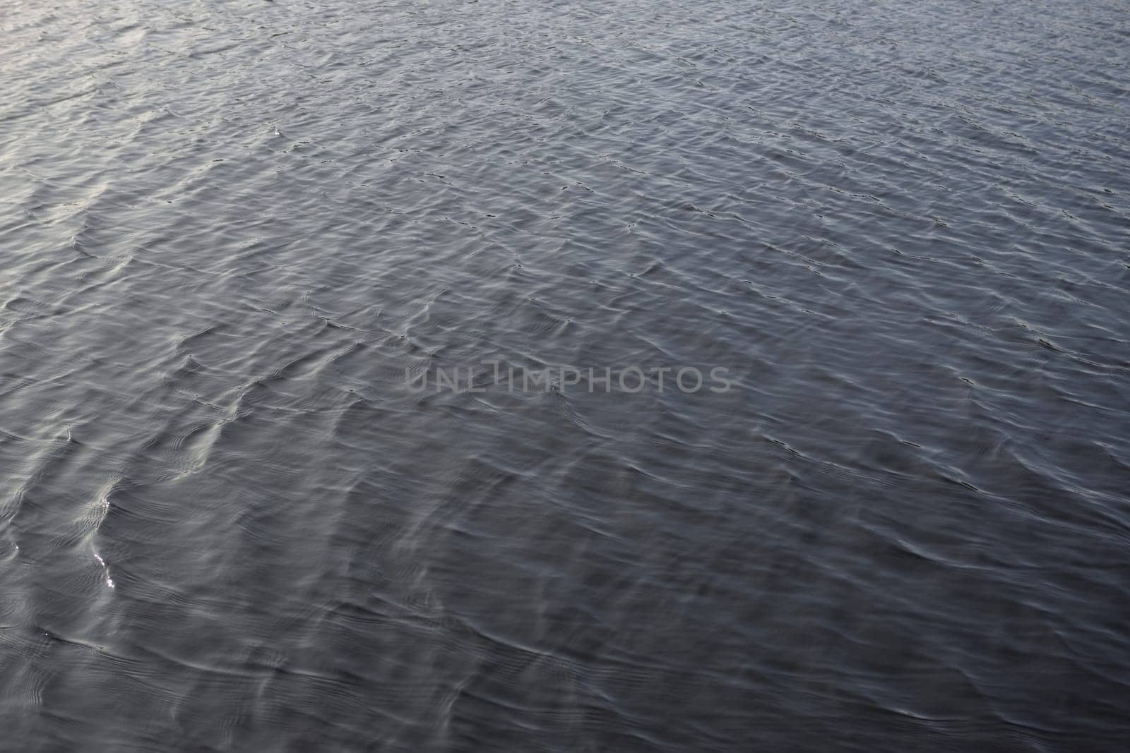 3 - Evening daytime full frame gently rippled lake water. smooth sunlight gives gradual colors across the frame.