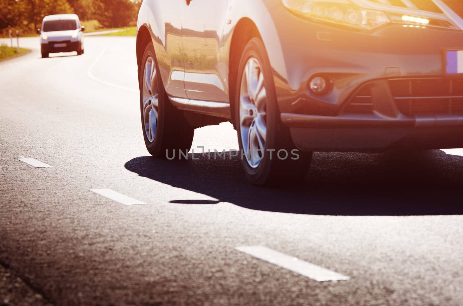 asphalt road view with a car in countryside at beautiful sunset