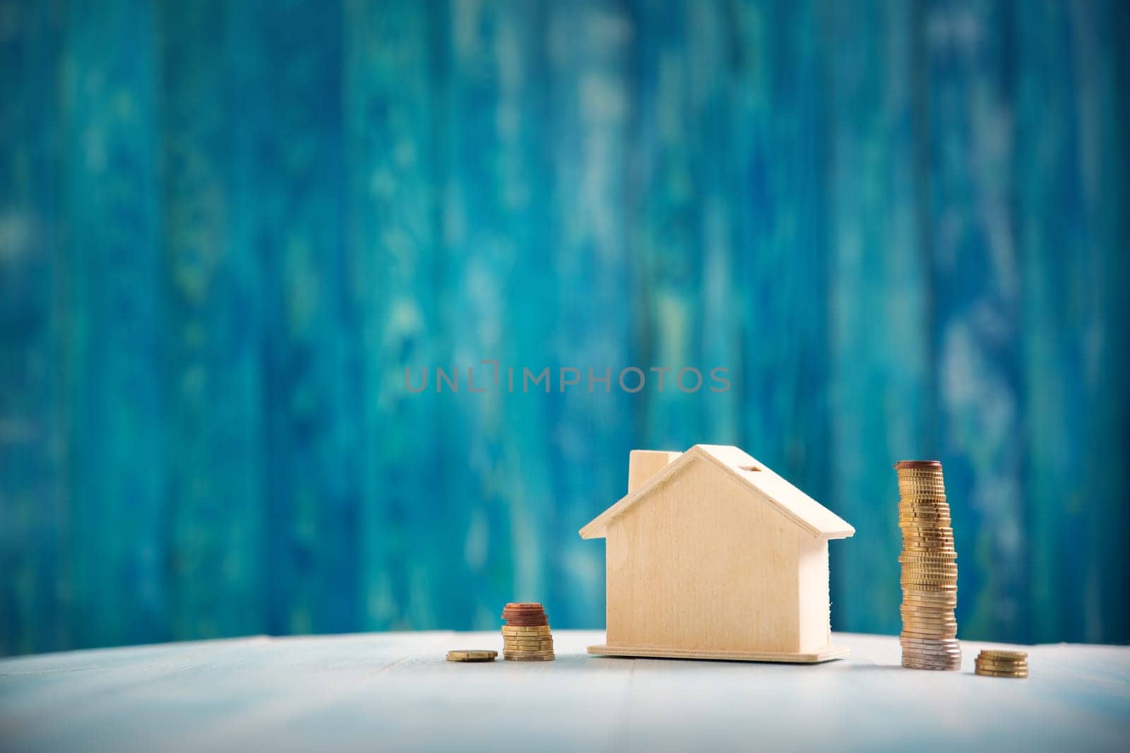 house model on wooden background with coins. Property price concept