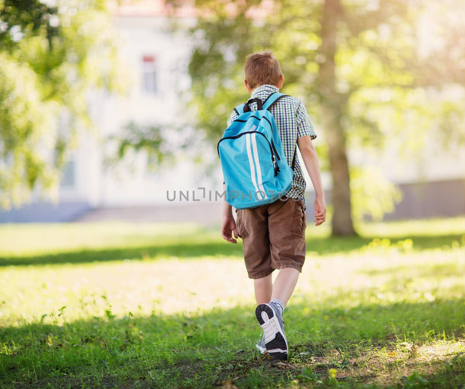 Boy with rucksack infront of a school building. Child with a backpack