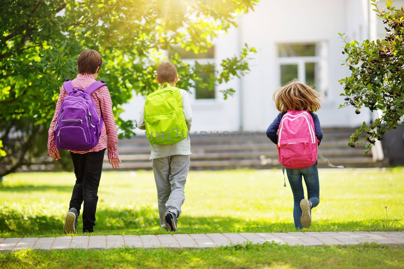 Children with rucksacks standing in the park near school. Pupils with books and backpacks outdoors