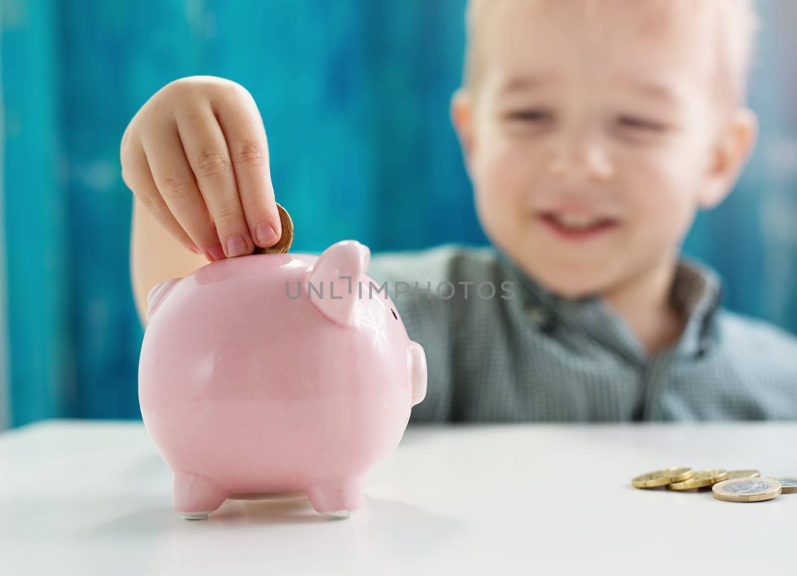 three years old child sitting st the table with money and piggybank. Happy boy with euro coins. Future childhood and education investment. Finance and savings concept