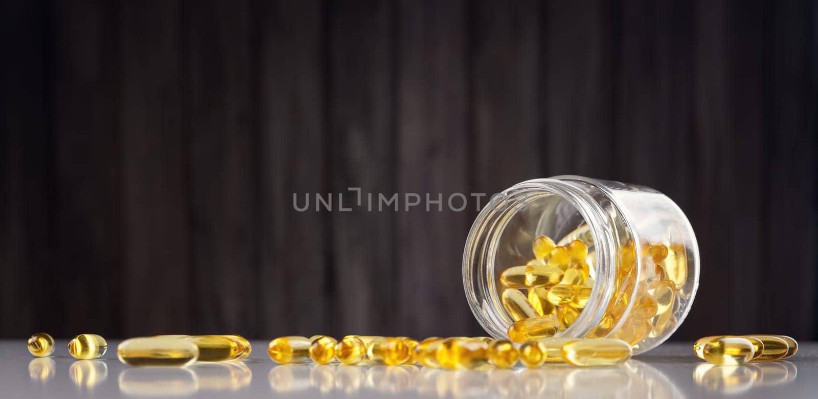 Pills in a jar on wooden background. D vitamin capsules with fish oil in a bottle