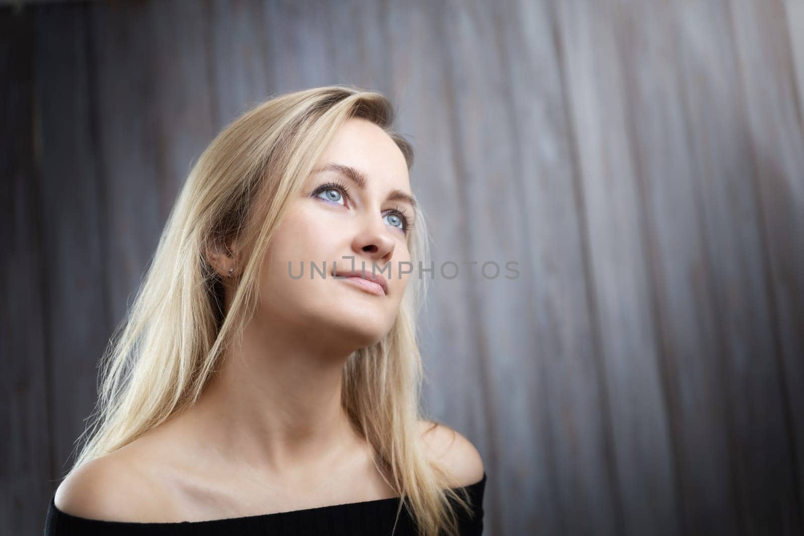 Happy beautiful young blond woman portrait with wooden background. Attractive girl in studio with long hair