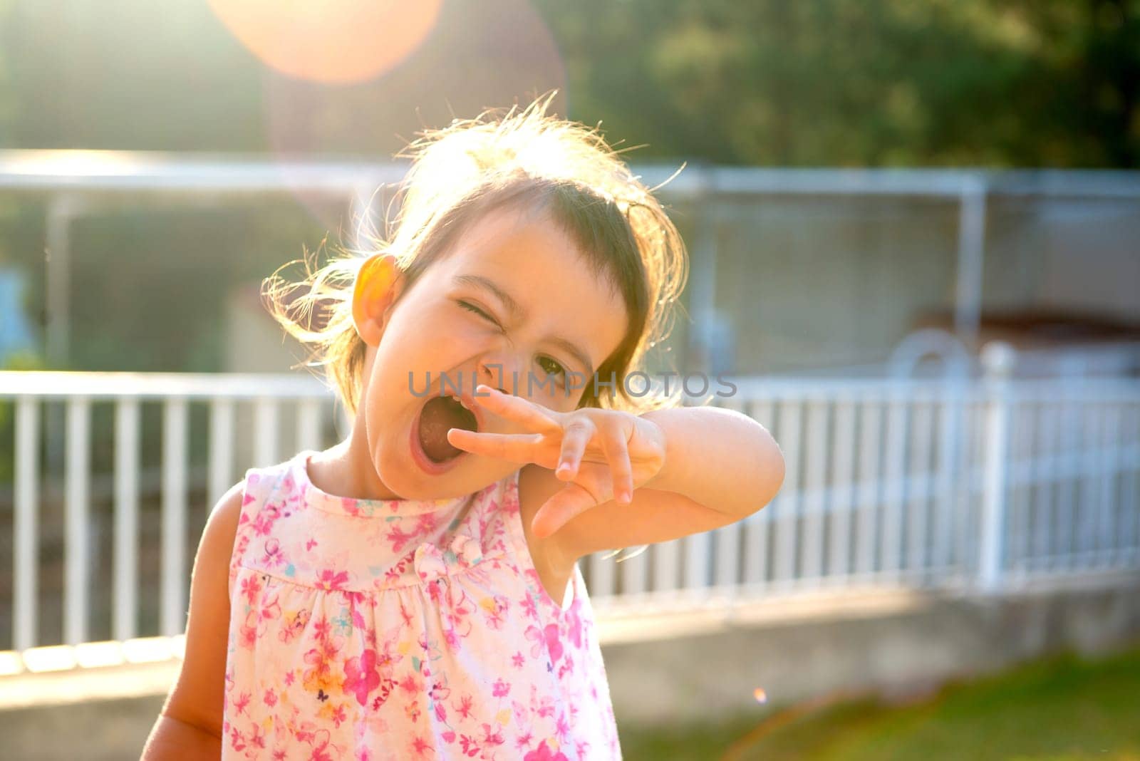 Sweet young girl making faces outdoors at sunset
