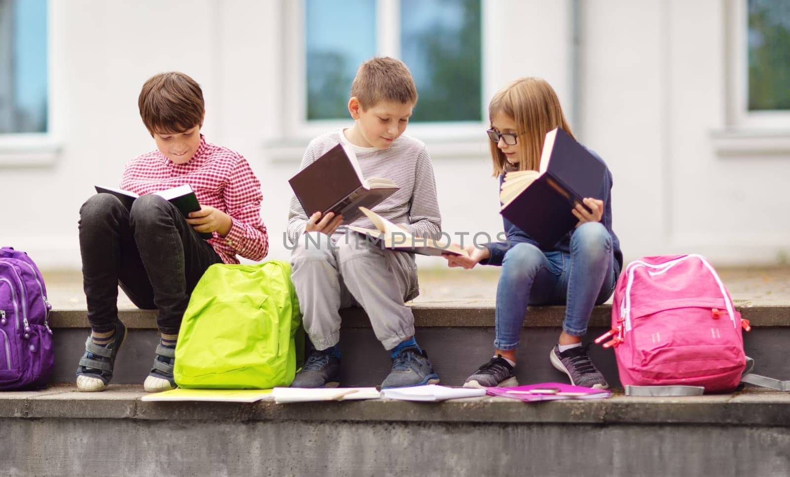 Children with rucksacks standing in the park near school. Pupils with books and backpacks outdoors