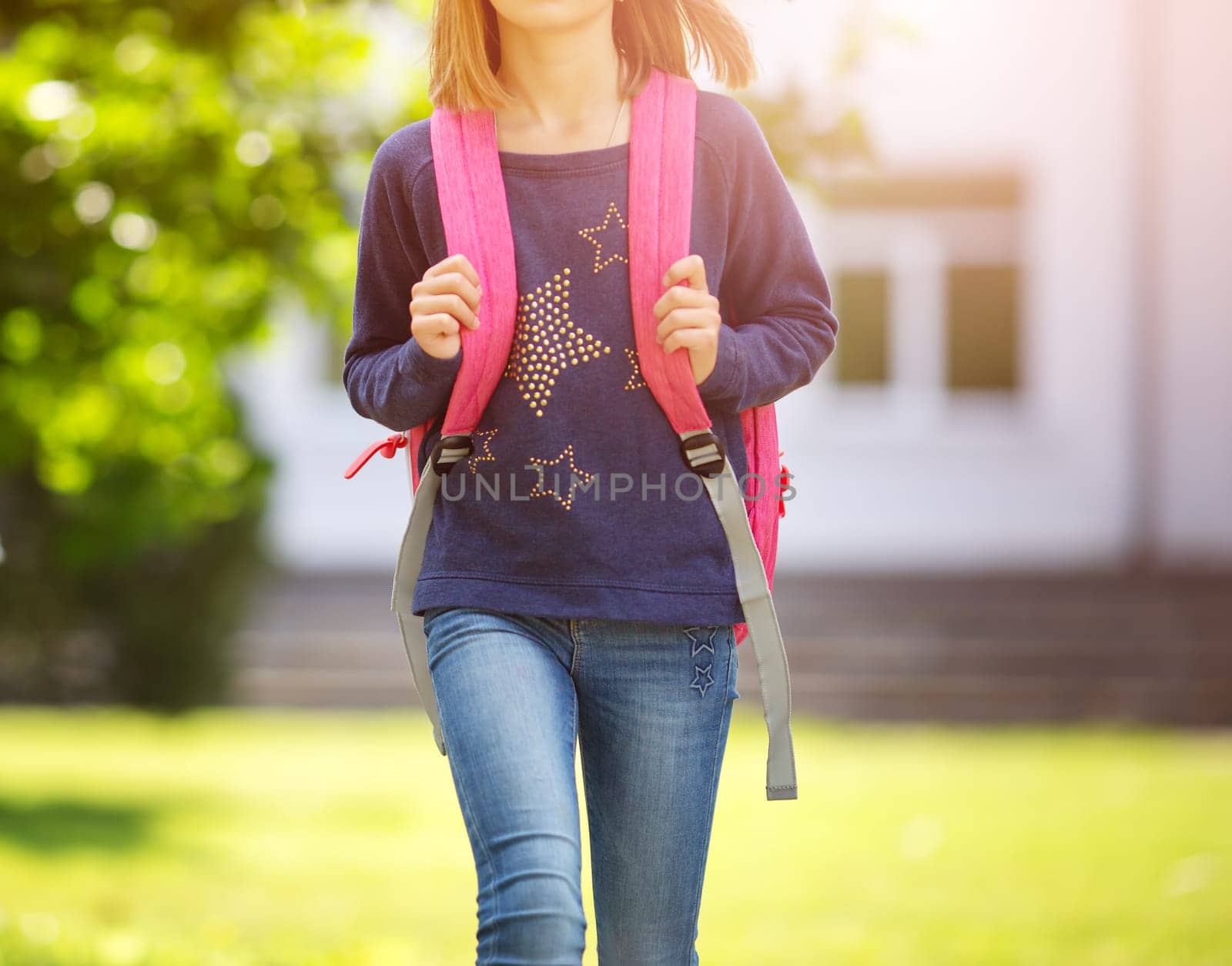 Girl with rucksack infront of a school building. Child with a backpack