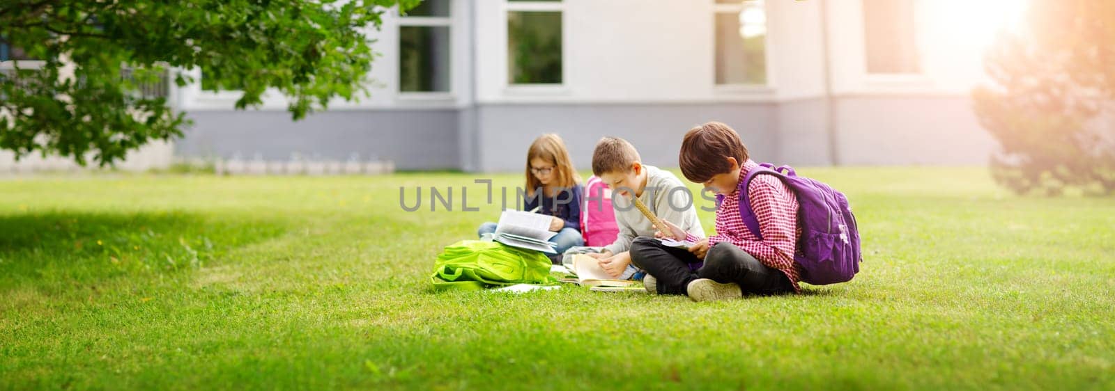 Children with rucksacks standing in the park near school. Pupils with books and backpacks outdoors