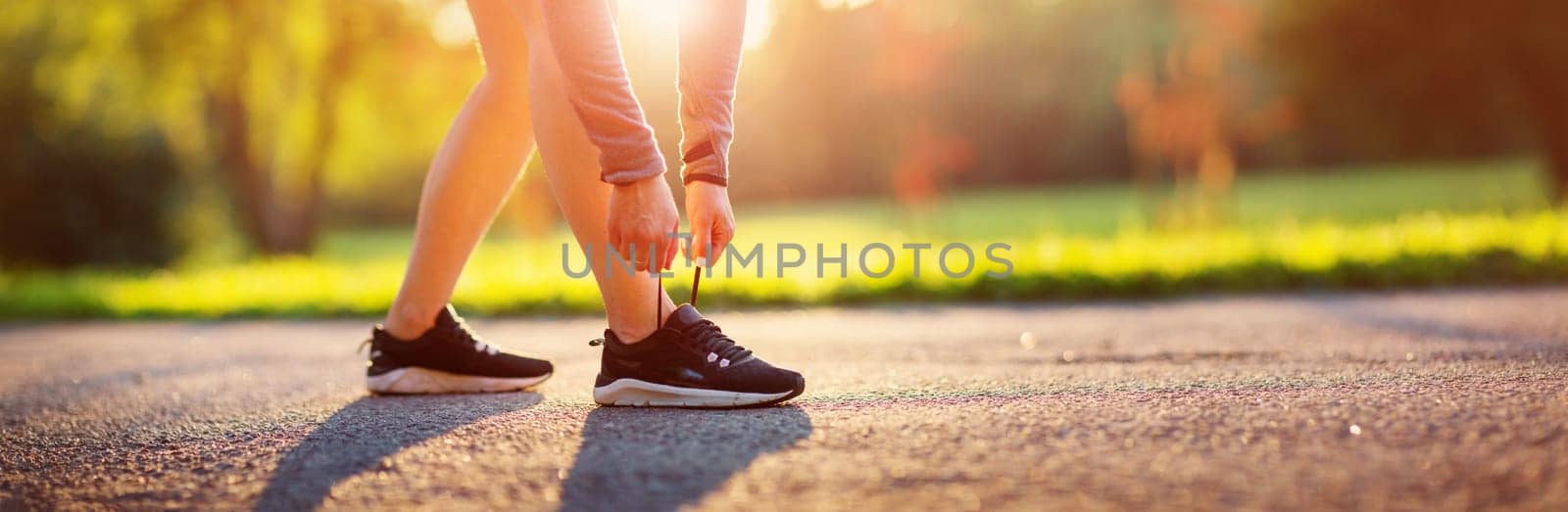 Young woman running in the park. Active person outdoors at the dusk in summer on asphalt road