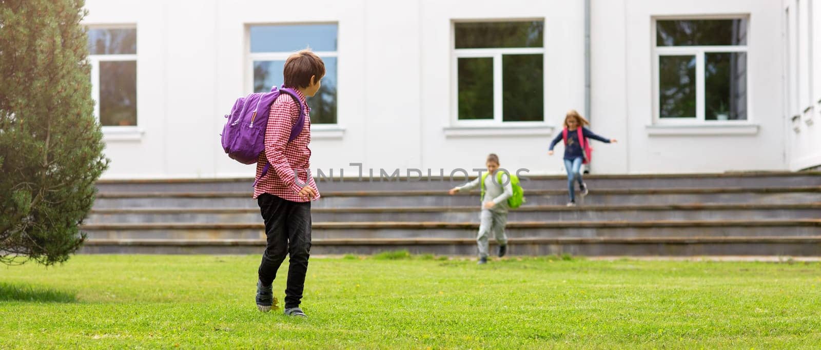 Children with rucksacks standing in the park near school. Pupils with books and backpacks outdoors