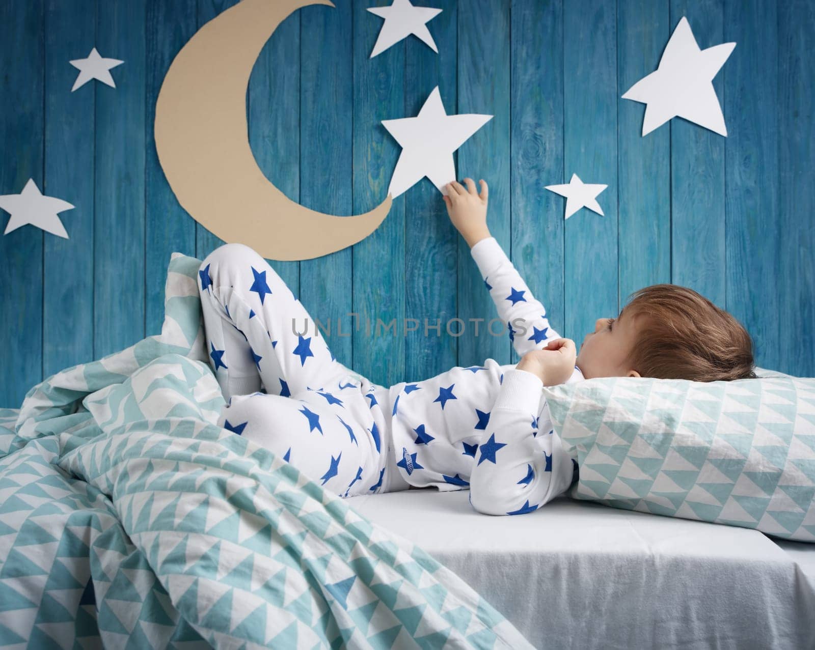Five years old child sleeping in bed. Boy lying with closed eyes at night