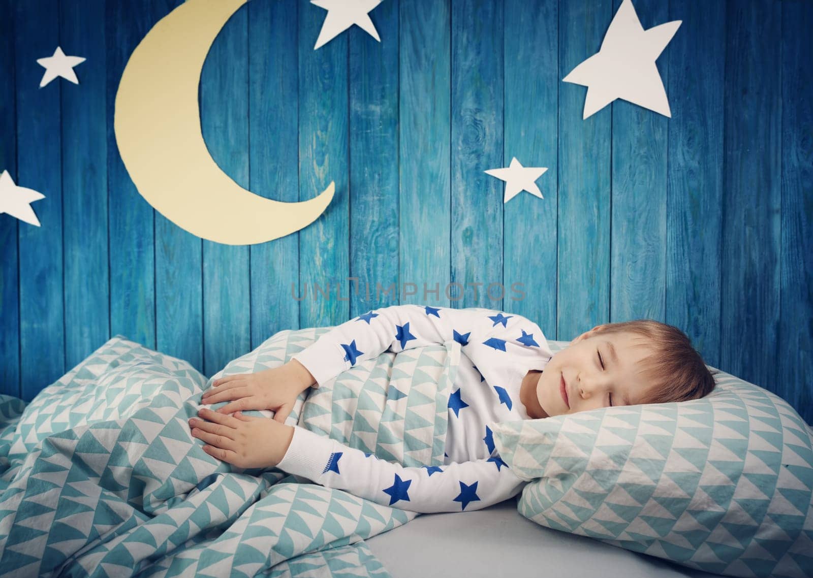 Five years old child sleeping in bed. Boy lying with closed eyes at night