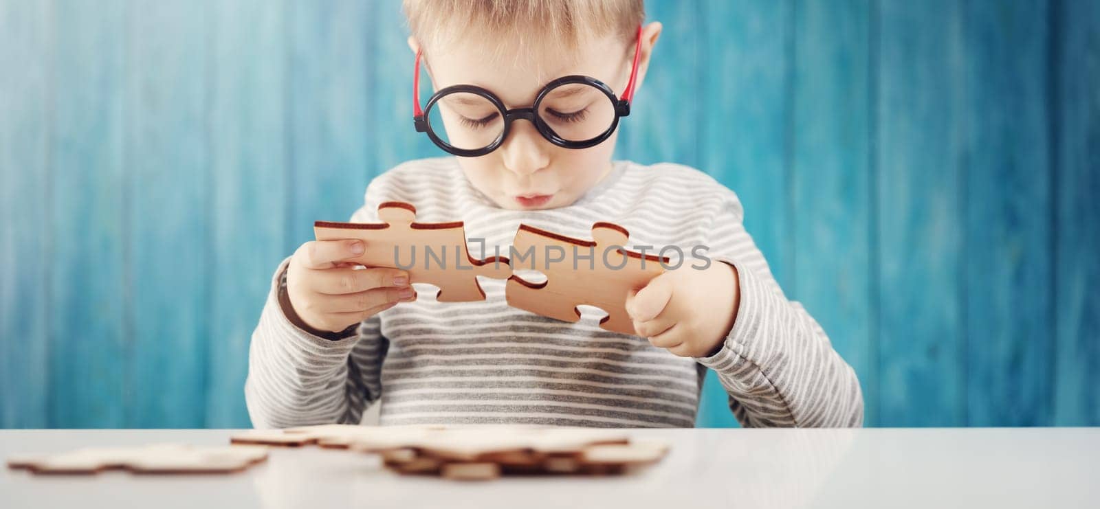 Little child holding puzzle pieces and trying to solve it. Problem solution concept