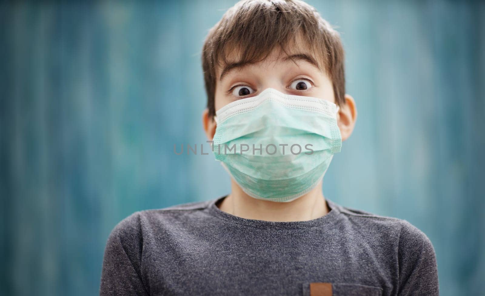 boy in medical face protection mask indoors on blue background. Sick child