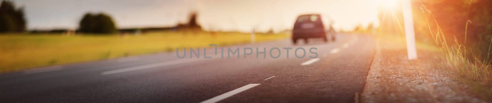 asphalt road view with a blurred car in countryside at beautiful sunset