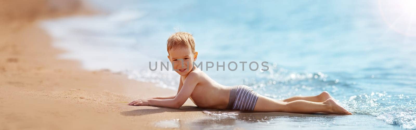Boy lying on the beach at sea in summer. Vacations at seaside