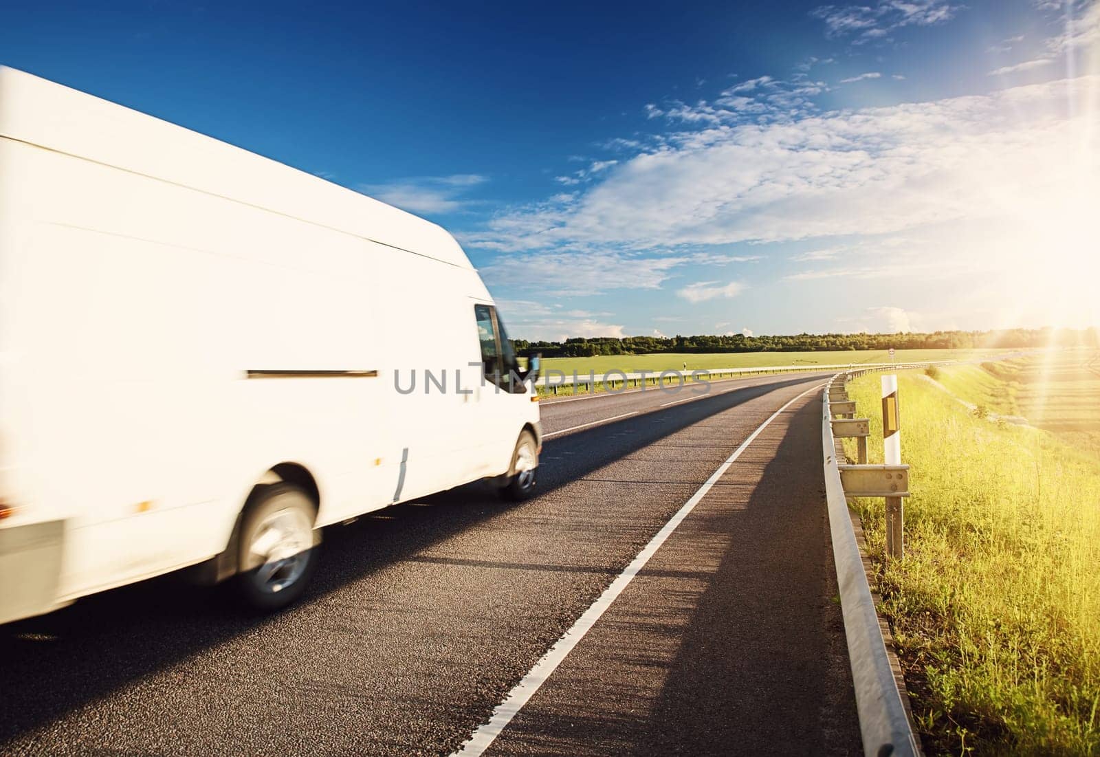 asphalt road on dandelion field with a small truck. white van moving on sunny summer evening on highway. Transportation and delivery concept