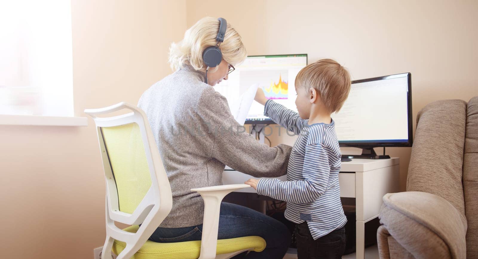 woman working at home with little child. Young businesswoman working indoors at pc