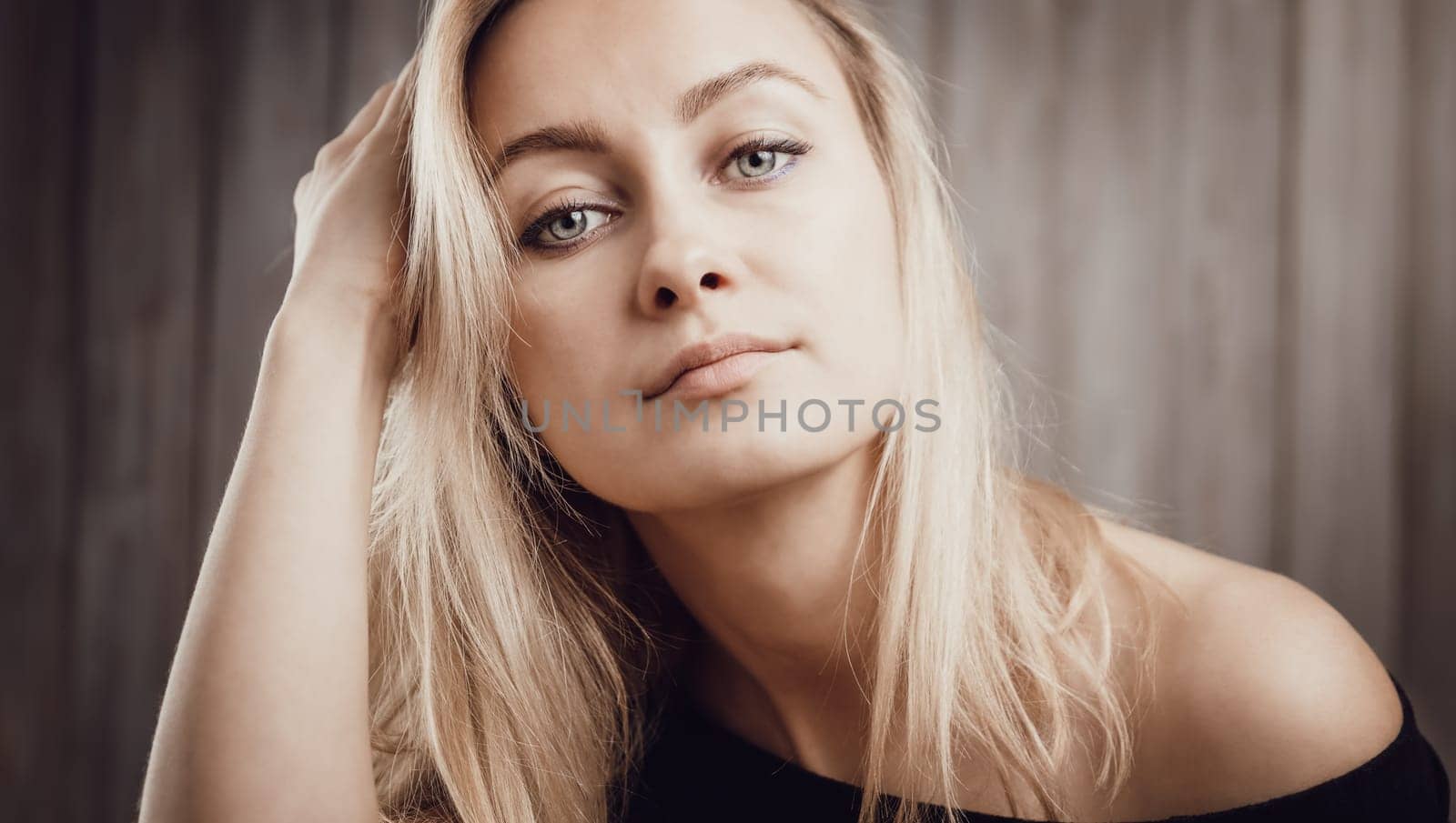 Happy beautiful young blond woman portrait with wooden background. Attractive girl in studio with long hair