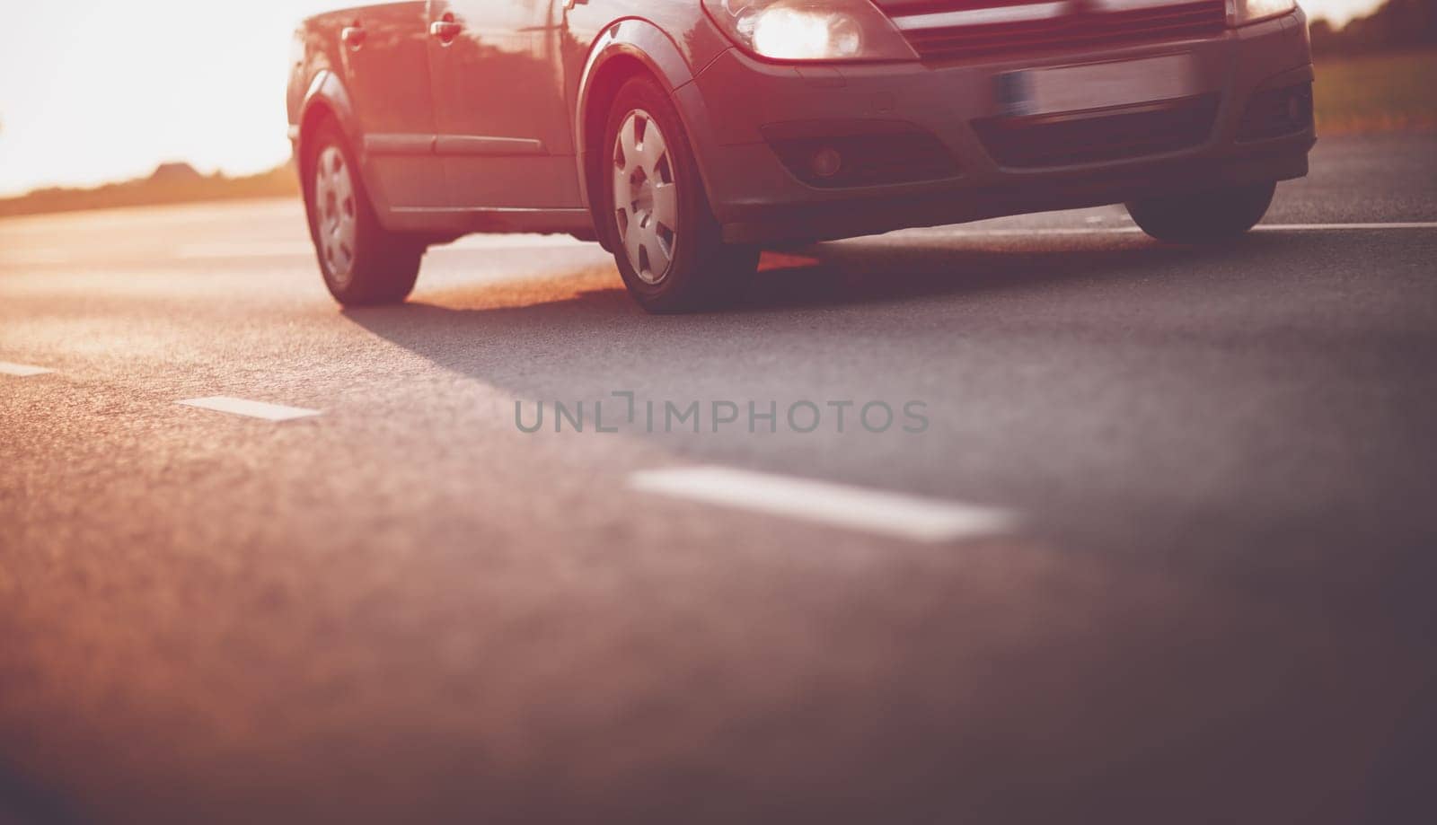 asphalt road view with a car in countryside at beautiful sunset