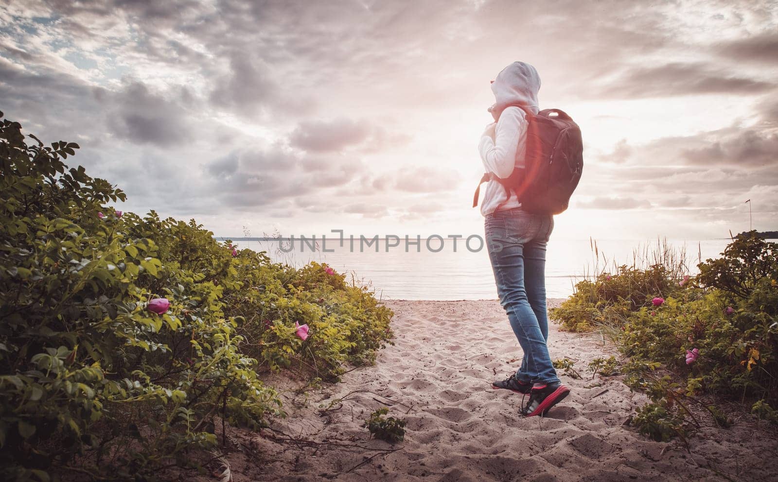 sea in sunset light. Woman in Lahemaa natural park coastal landscape with beautiful sky. Person with rucksack