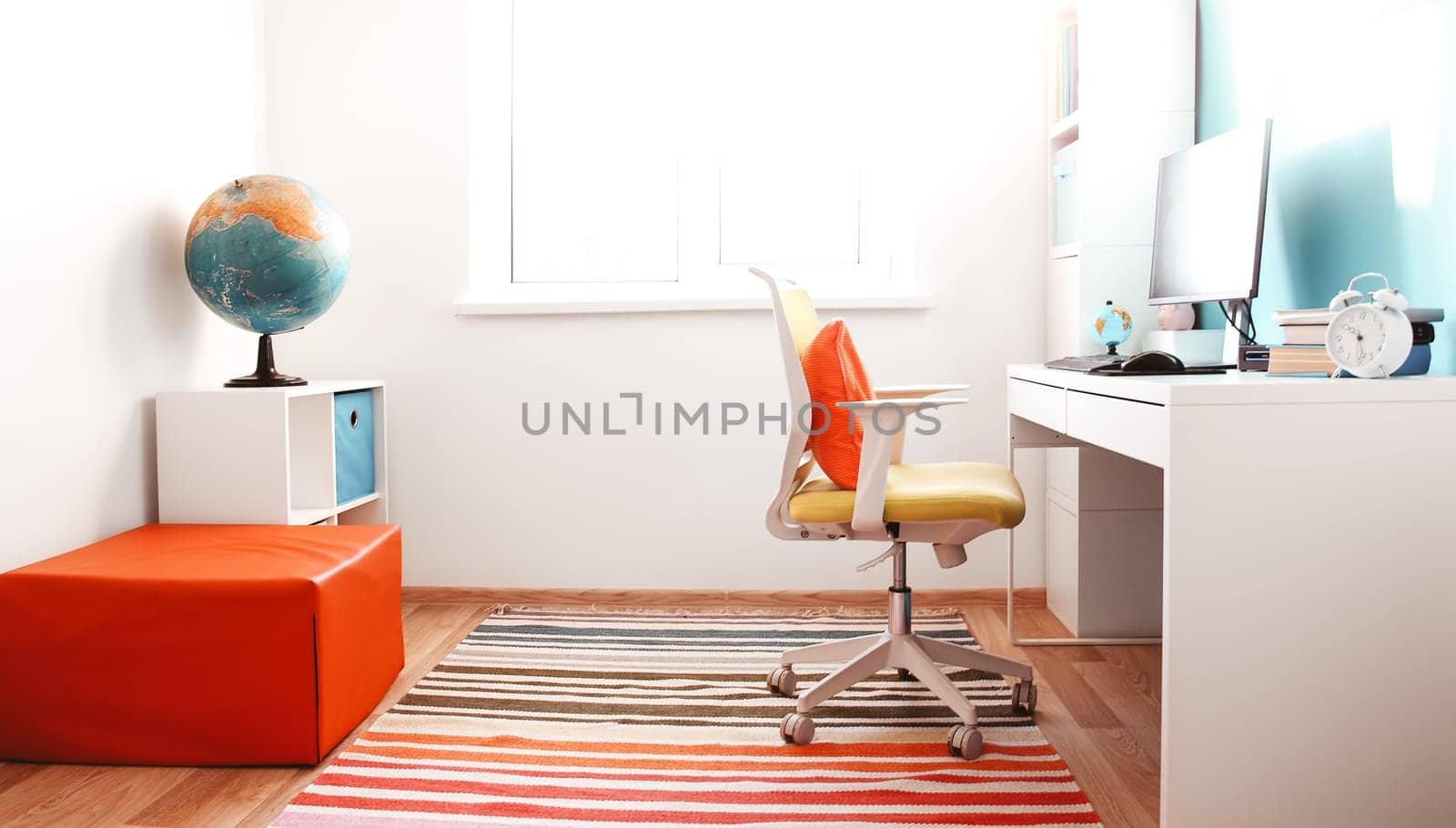 Colourful children rooom with white walls and furniture. Desk at home interior with a window