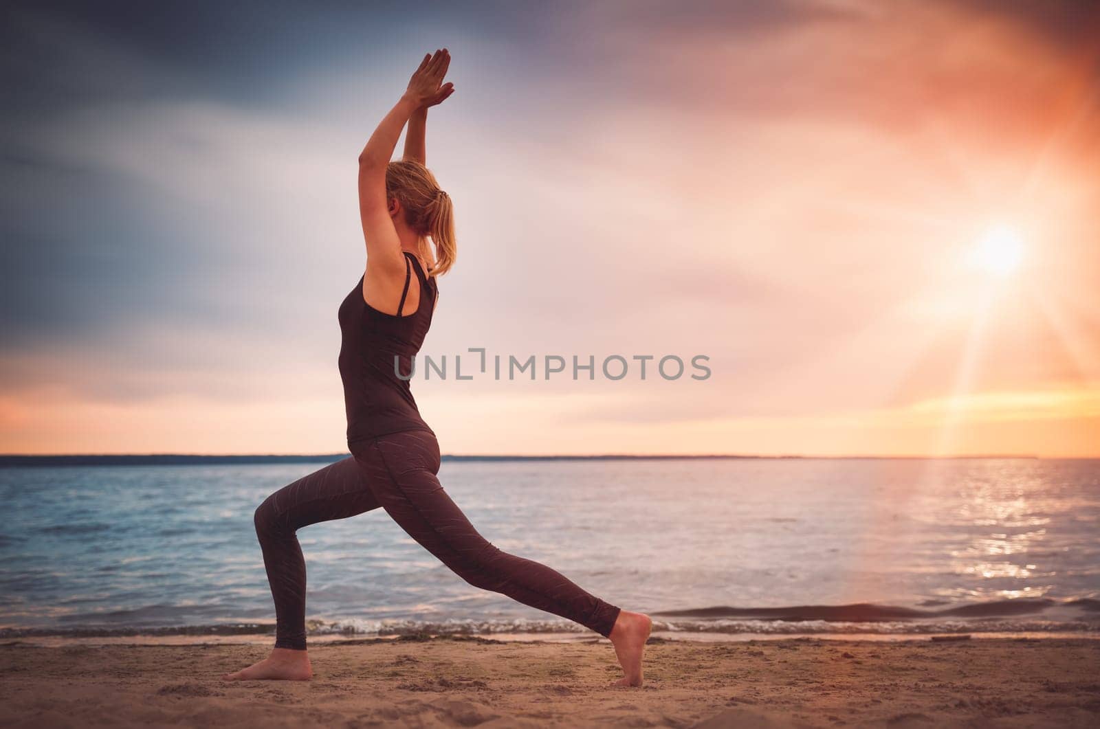 young woman sitting on the beach and practicing yoga
