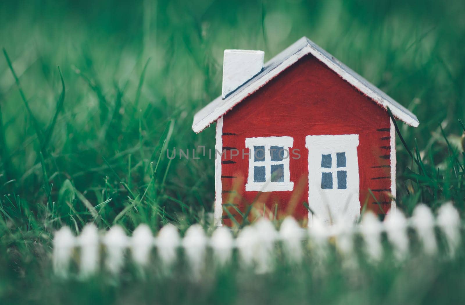 red wooden house model on the grass in garden