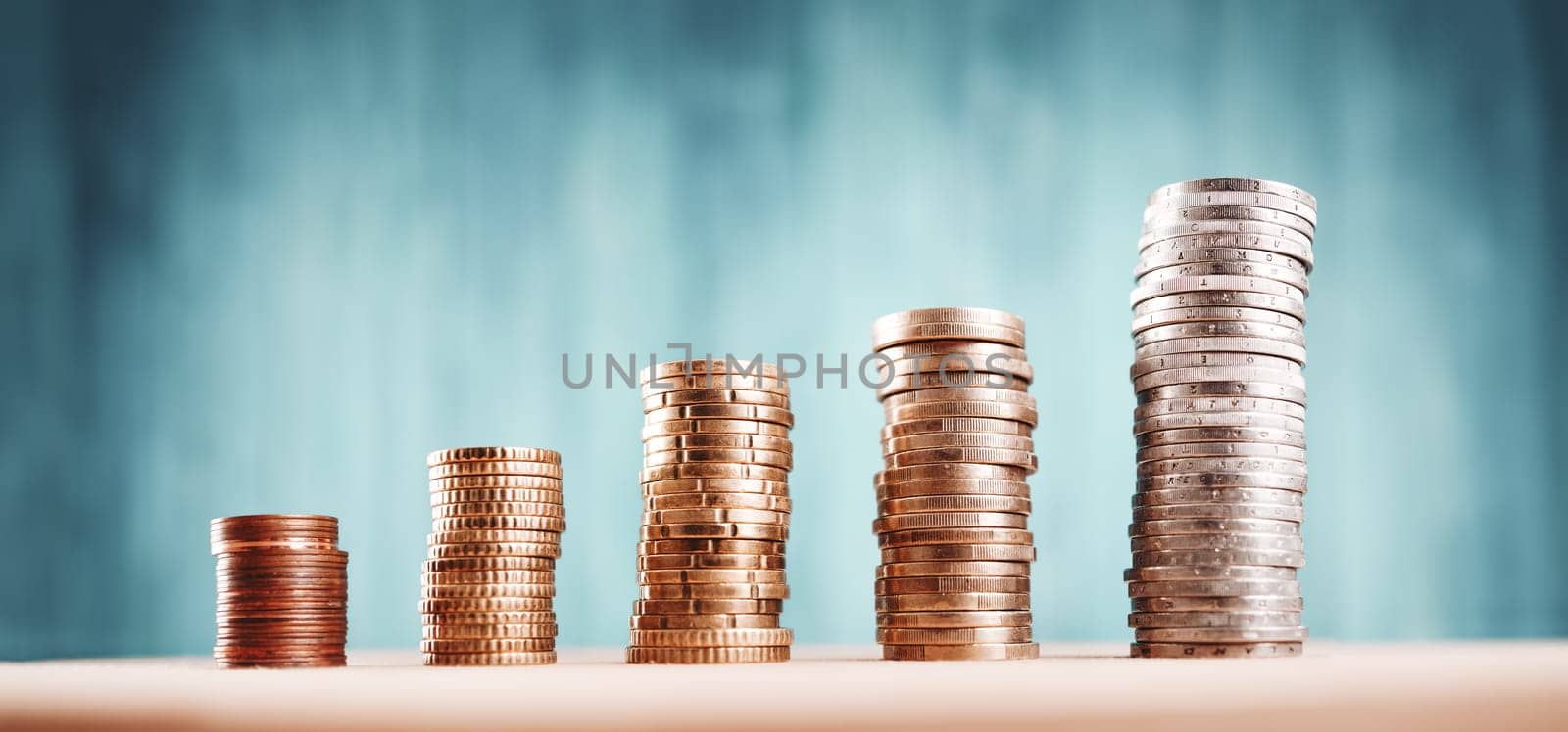 stacked coins on blue background. Money columns with different heigth