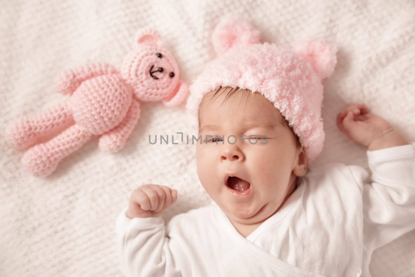Cute newborn baby girl lying in the bed. Two month old infant child on white soft blanket with teddy bear