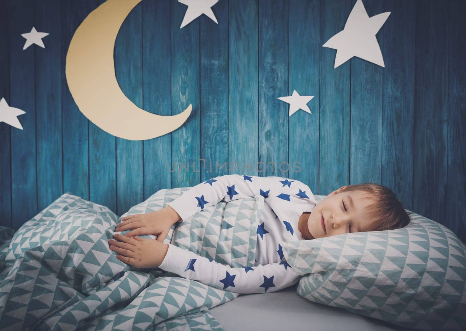 Five years old child sleeping in bed. Boy lying with closed eyes at night