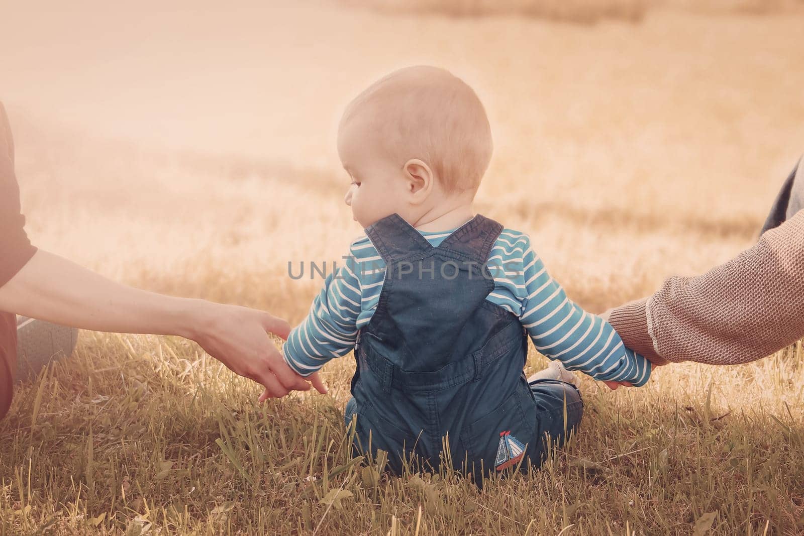 Baby with mother and father holding hands on the nature