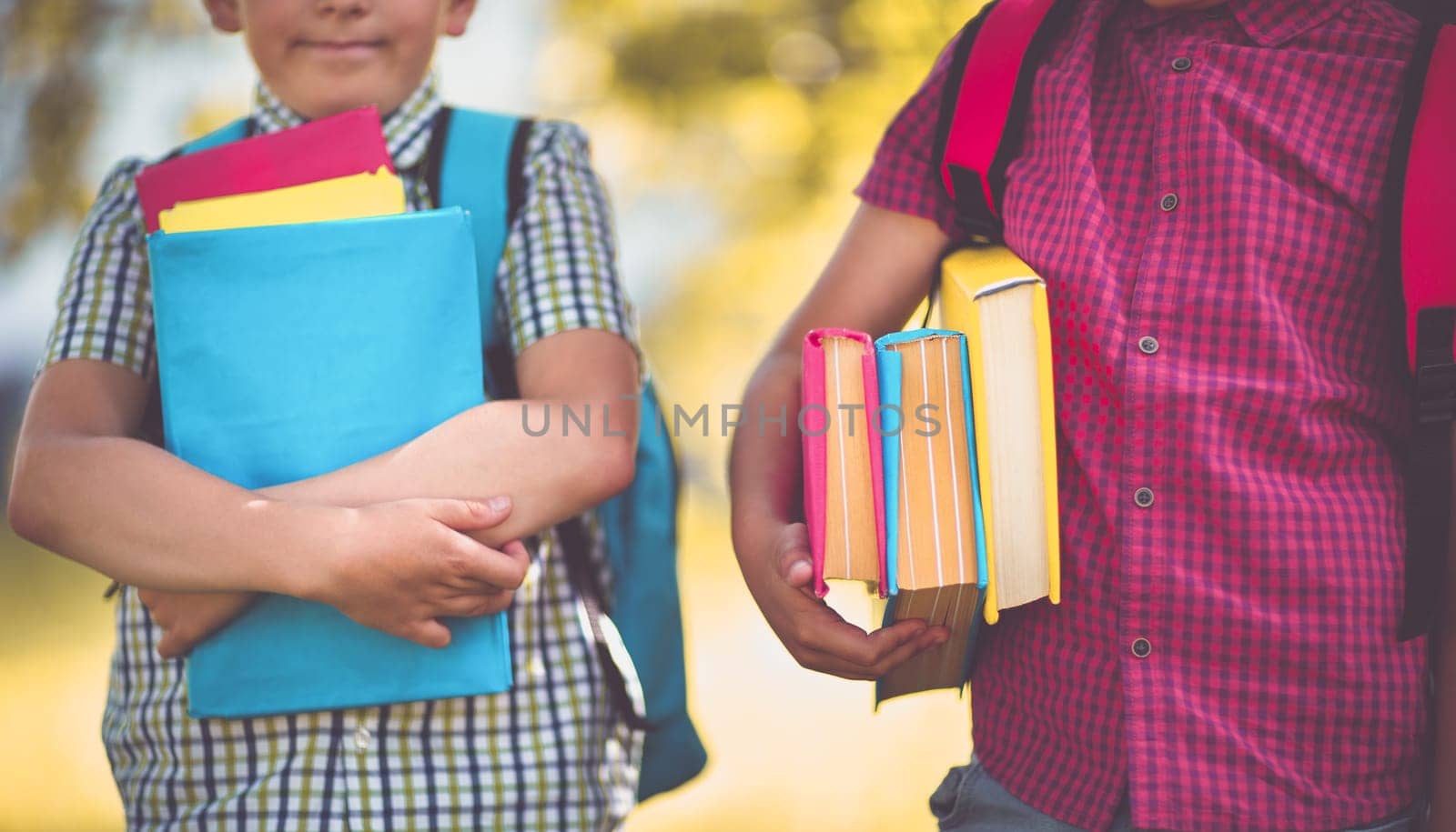 Children with rucksacks standing in the park near school. Pupils with books and backpacks outdoors