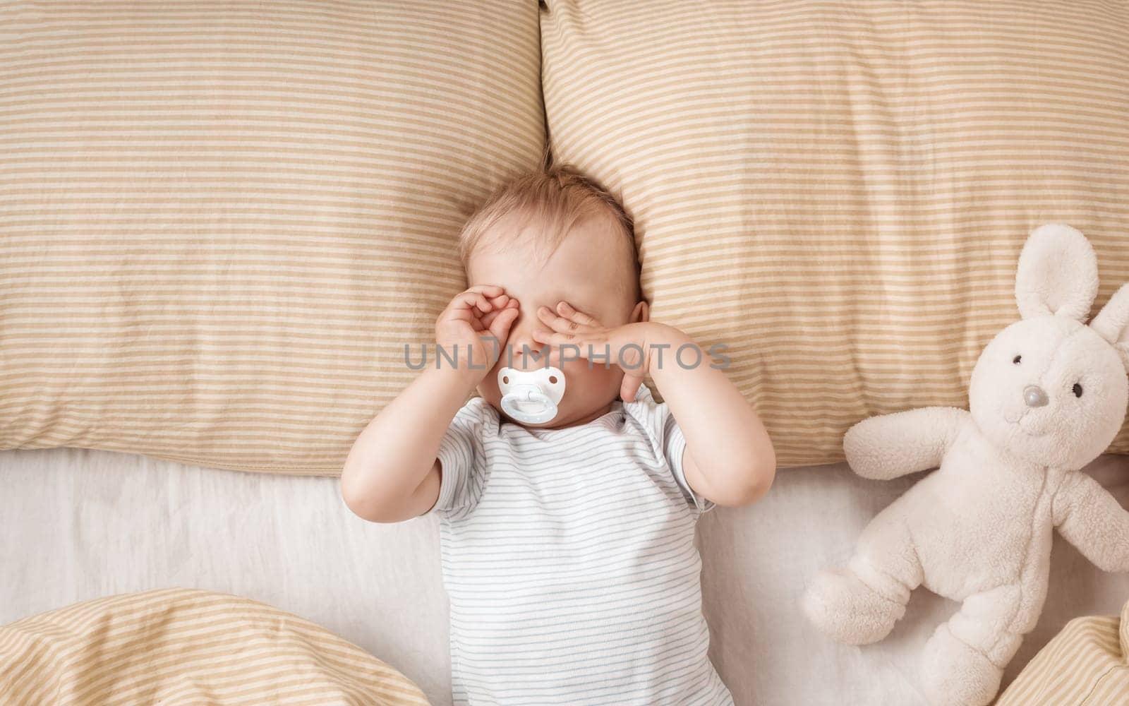 One year old baby lying in the bed with green bedding