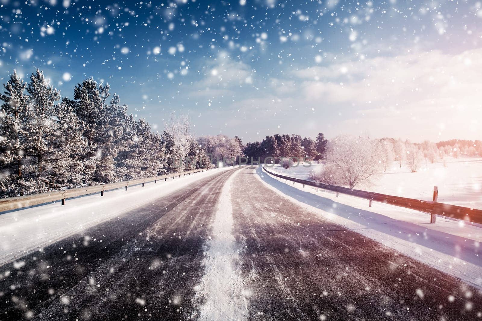 winter road, covered with snow on sunny day. Black icy asphalt