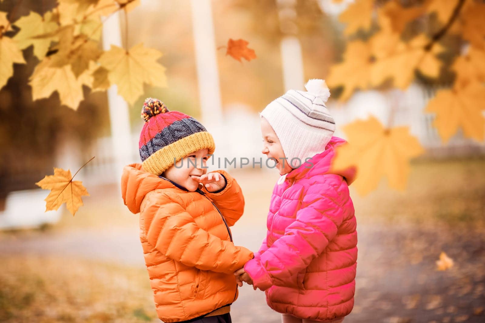 children having fun in beautiful autumnal day. Boy and girl playing outdoors in the park
