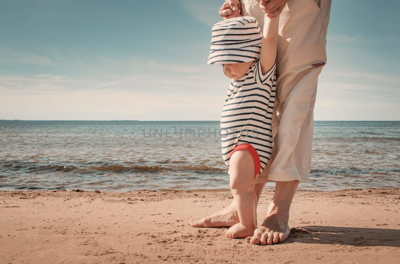 Nine month old baby boy walking on the beach in beautiful summer day