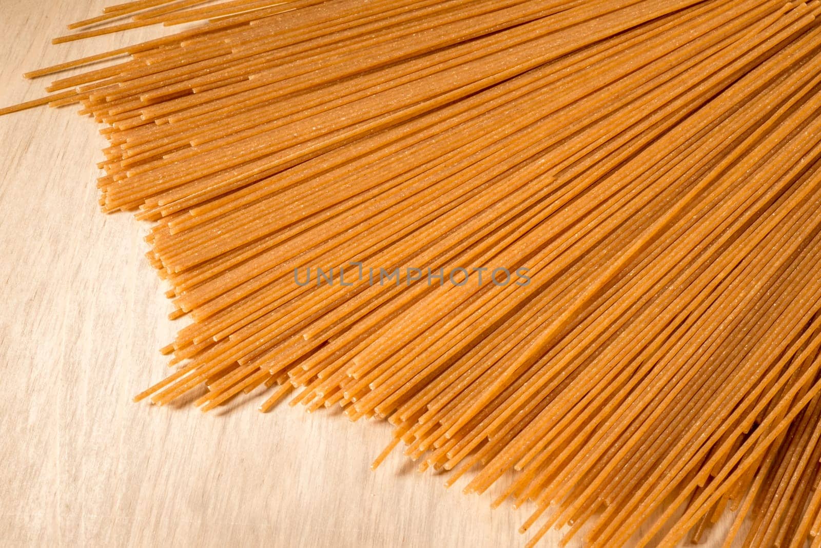 Wholewheat Spaghetti lies spread out on a wooden table.