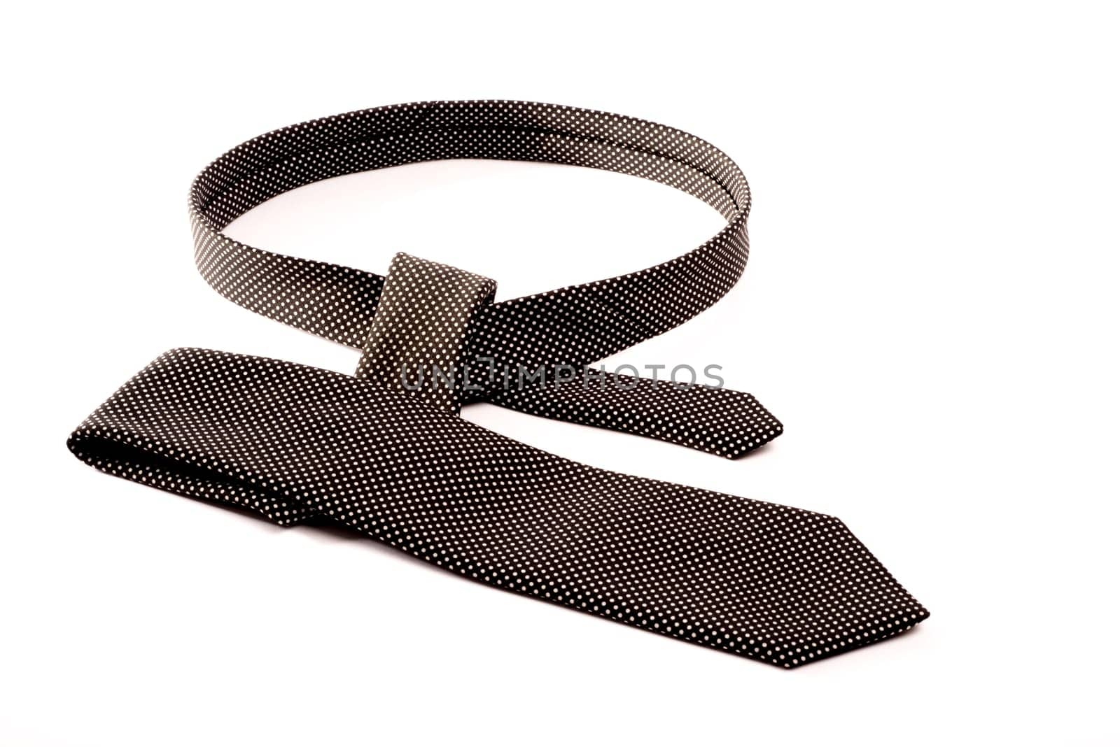 A black and white tie on a white isolated background in the process of being tied.