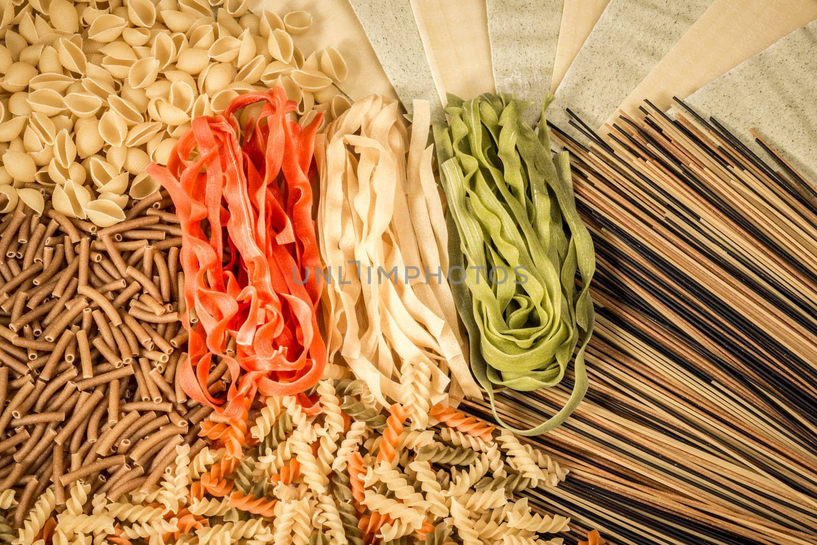 Different kinds of pasta spread over the table with the colours of the Italian flag in the middle