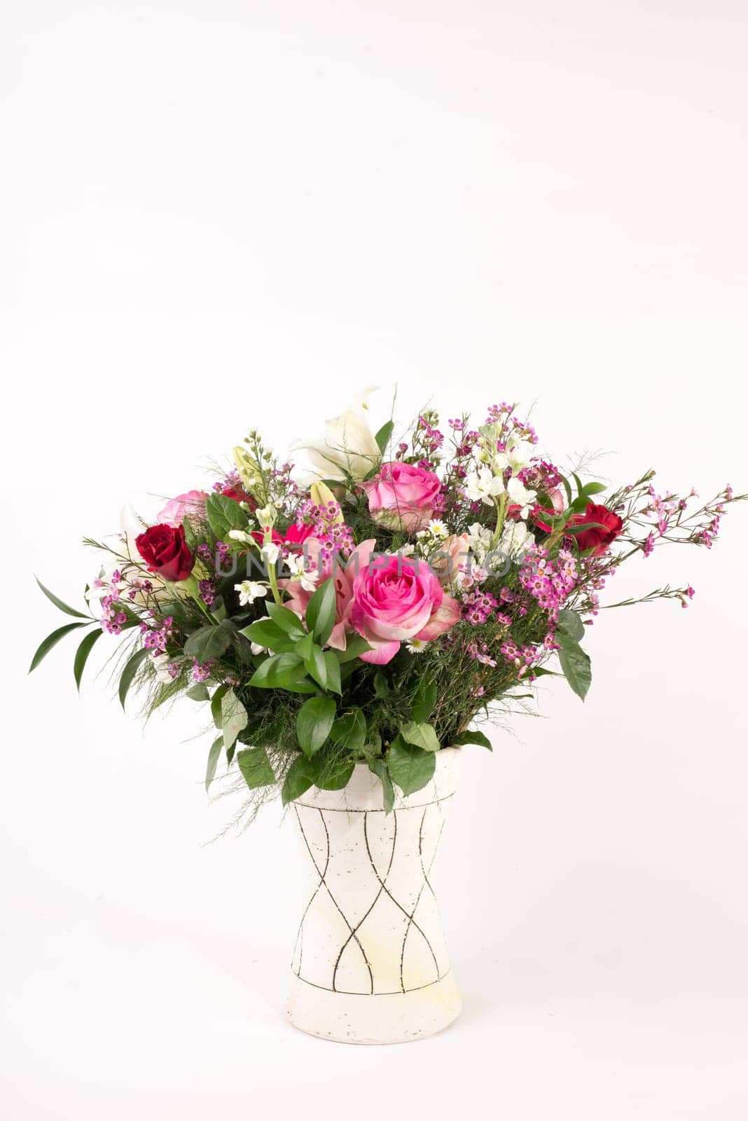 A beautiful flower arrangement in a vase set on a white islolated background.