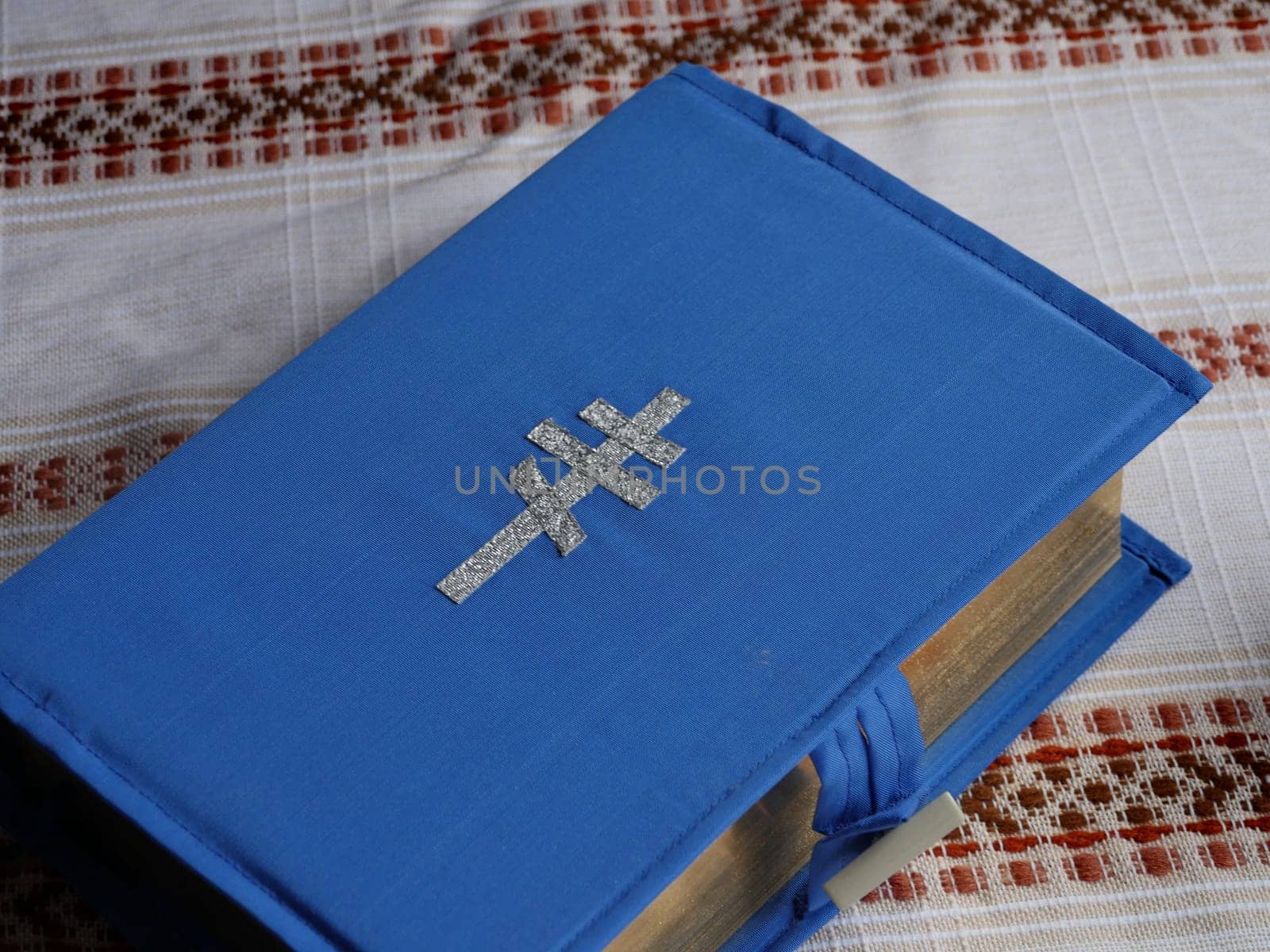 bible book in a blue cover with an embroidered silver cross on a table