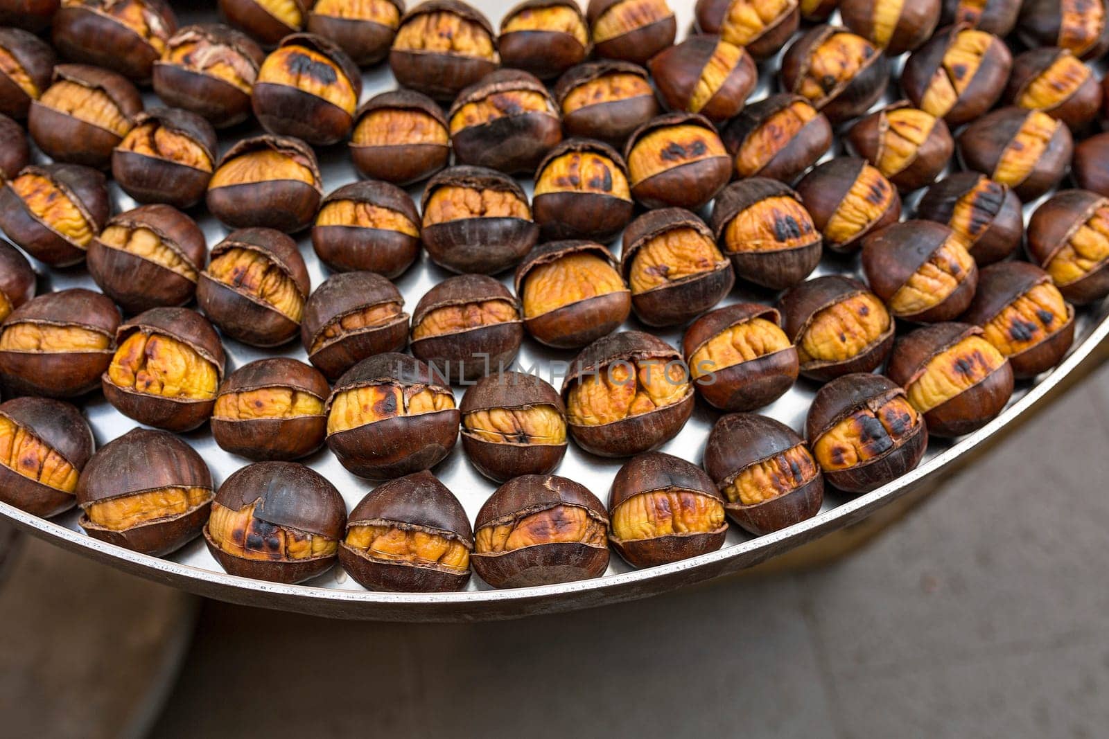 Roasted chestnuts nicely laid out on an iron tray. Close up, top view.