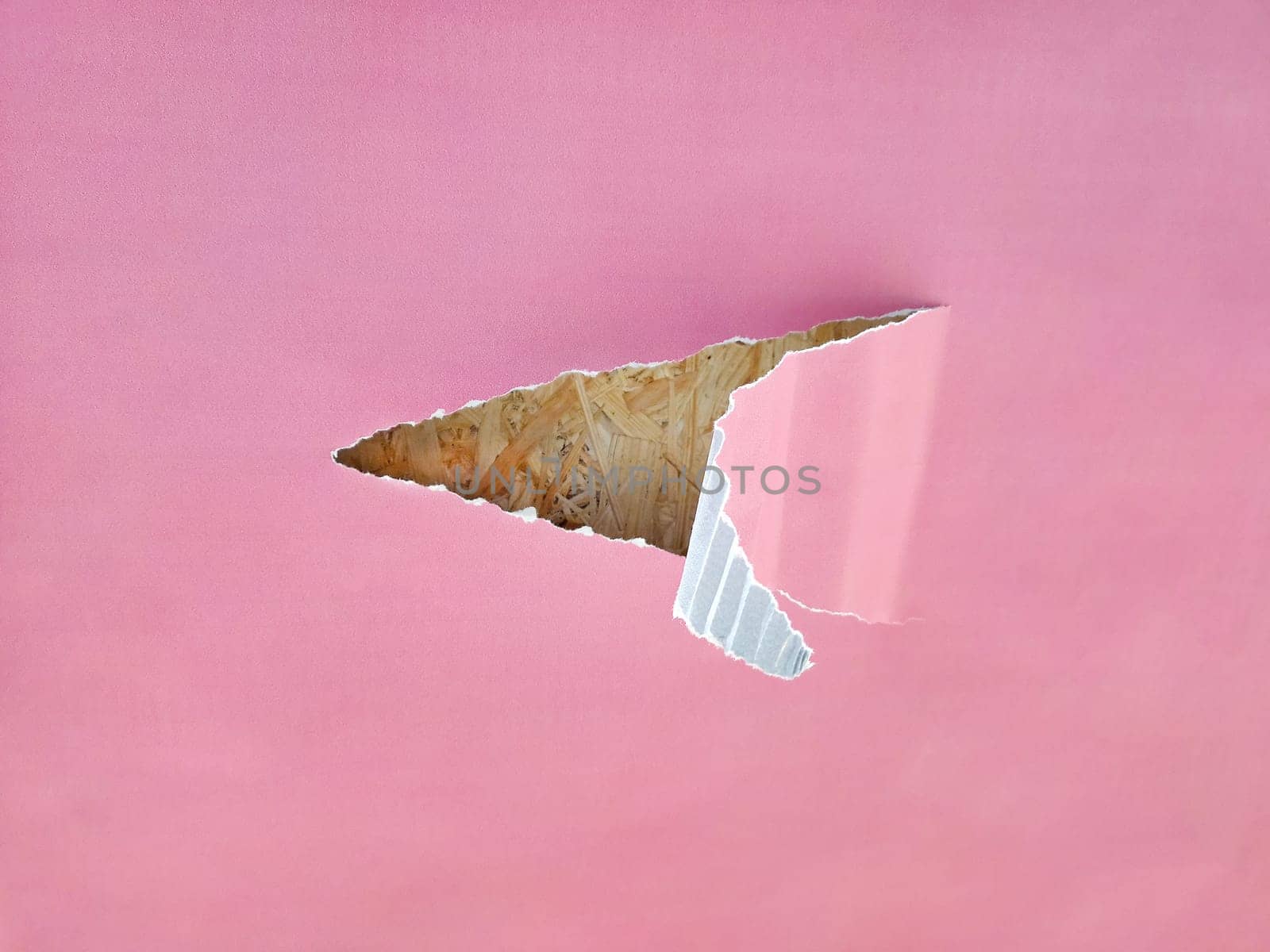 A sheet of corrugated paper, a piece in the middle is torn off and the edge is bent. An angry blue paper is visible in the hole. A piece of paper.