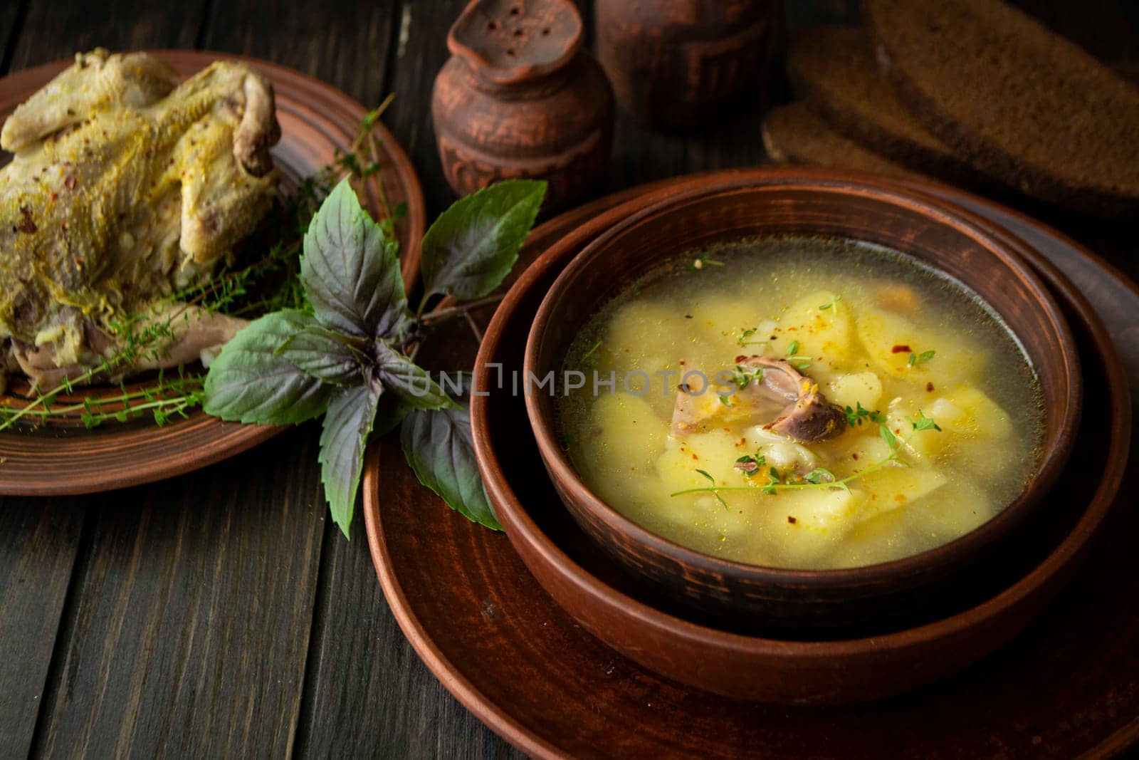 Partridge soup with basil in a rustic bowl on dark wooden table