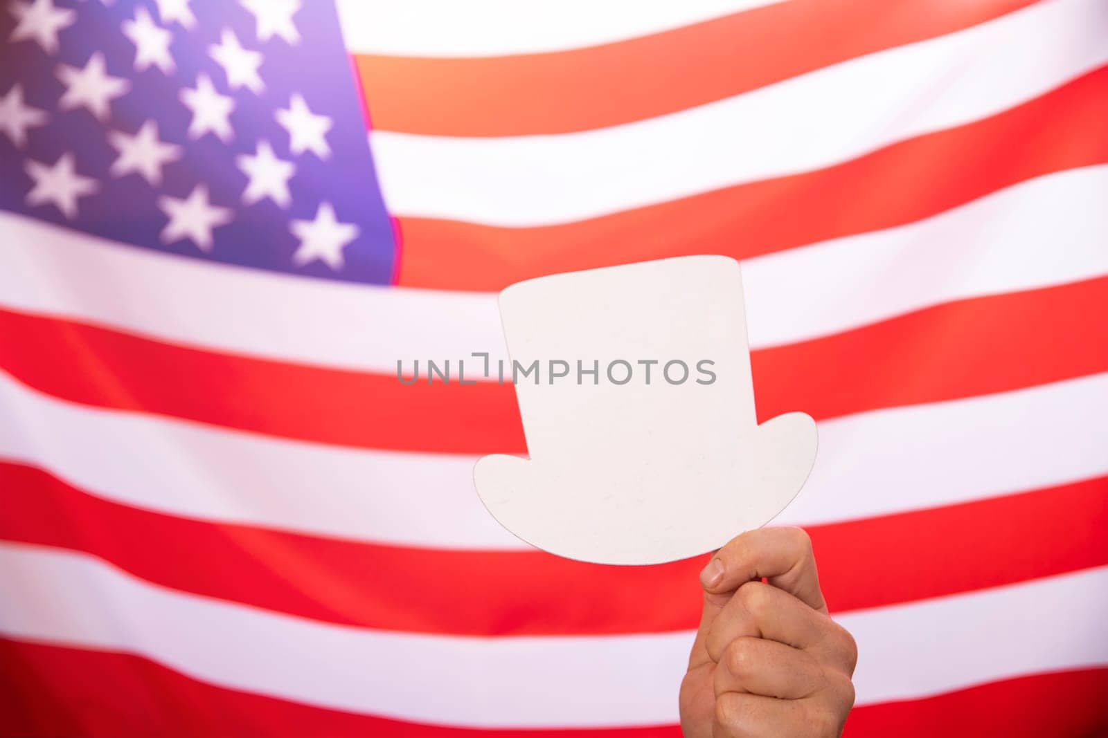 Hand holding white sign boards with US flag as background - Concept of US election.