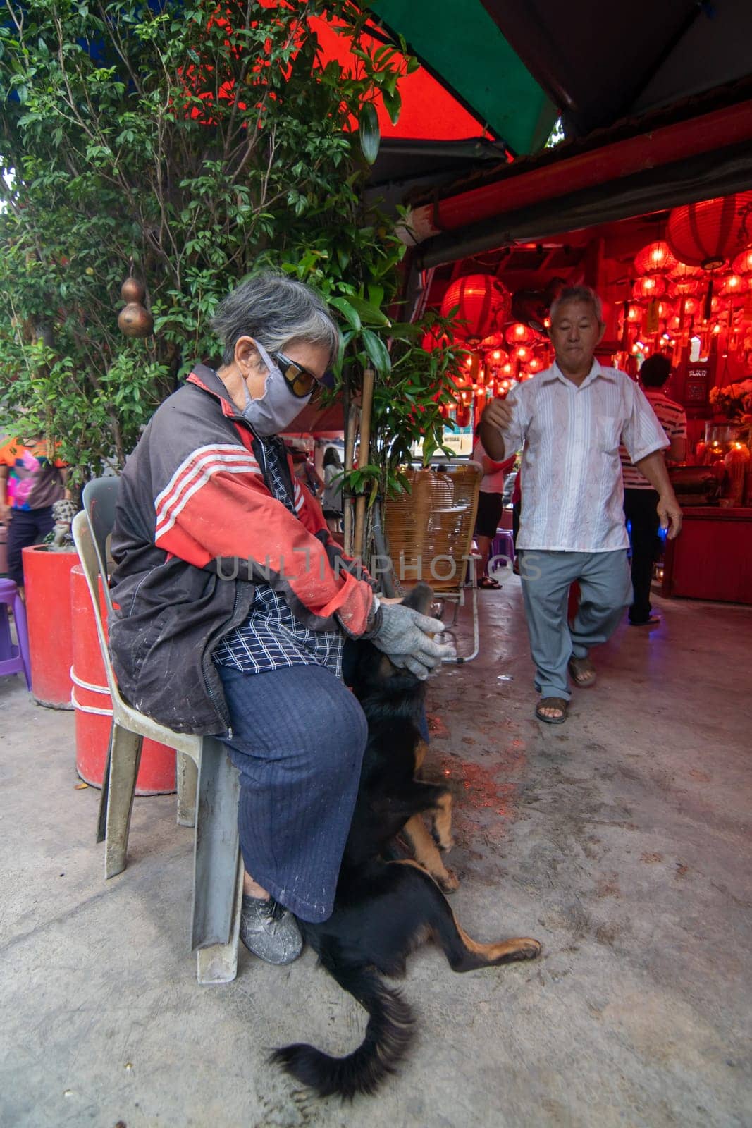 George Town, Penang/Malaysia - Jul 31 2018: An elder with dog near chinese temple.