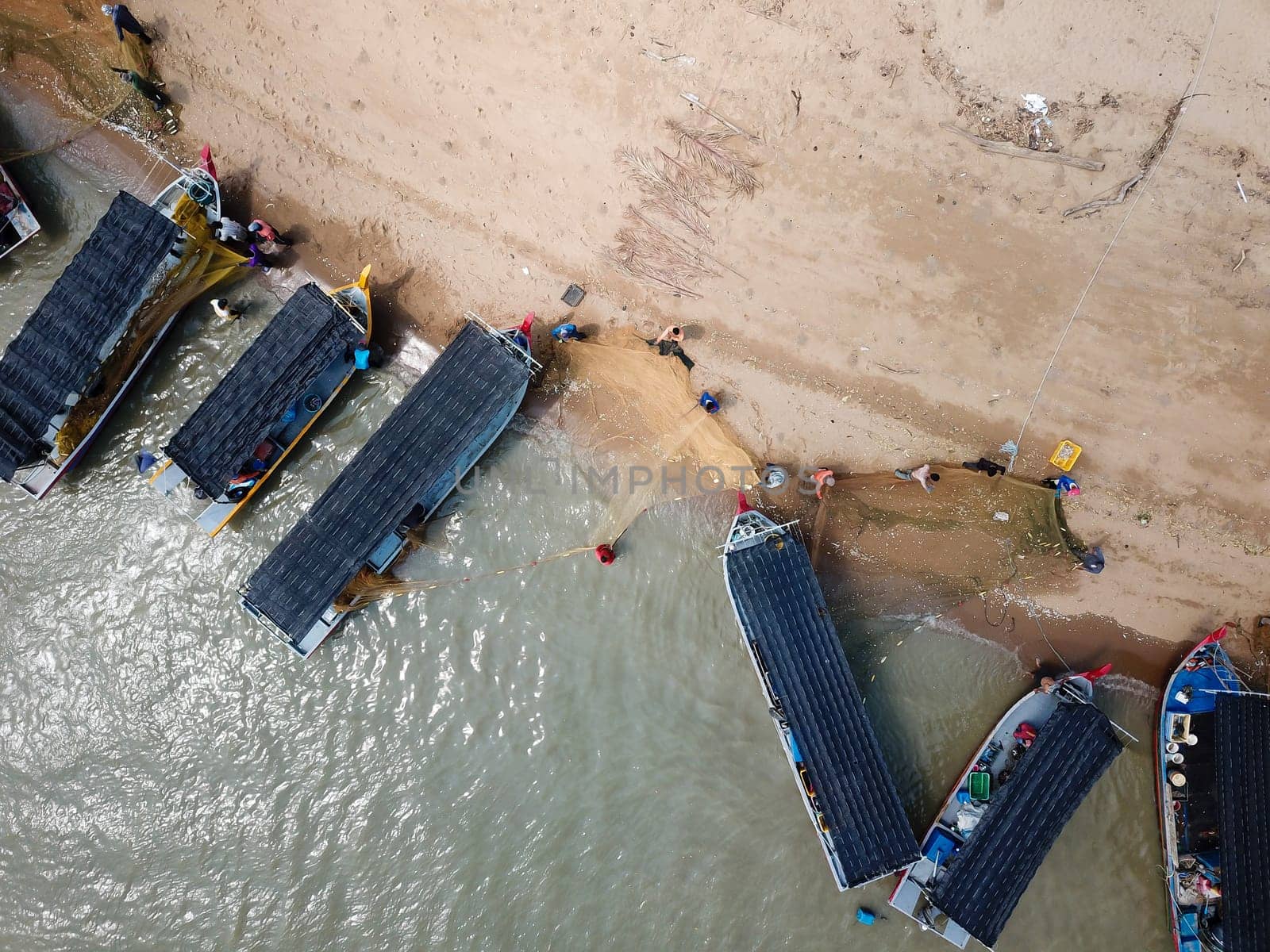 Kuala Muda, Penang/Malaysia - May 24 2019: Aerial view fisherman clear the small fish trap at the net.