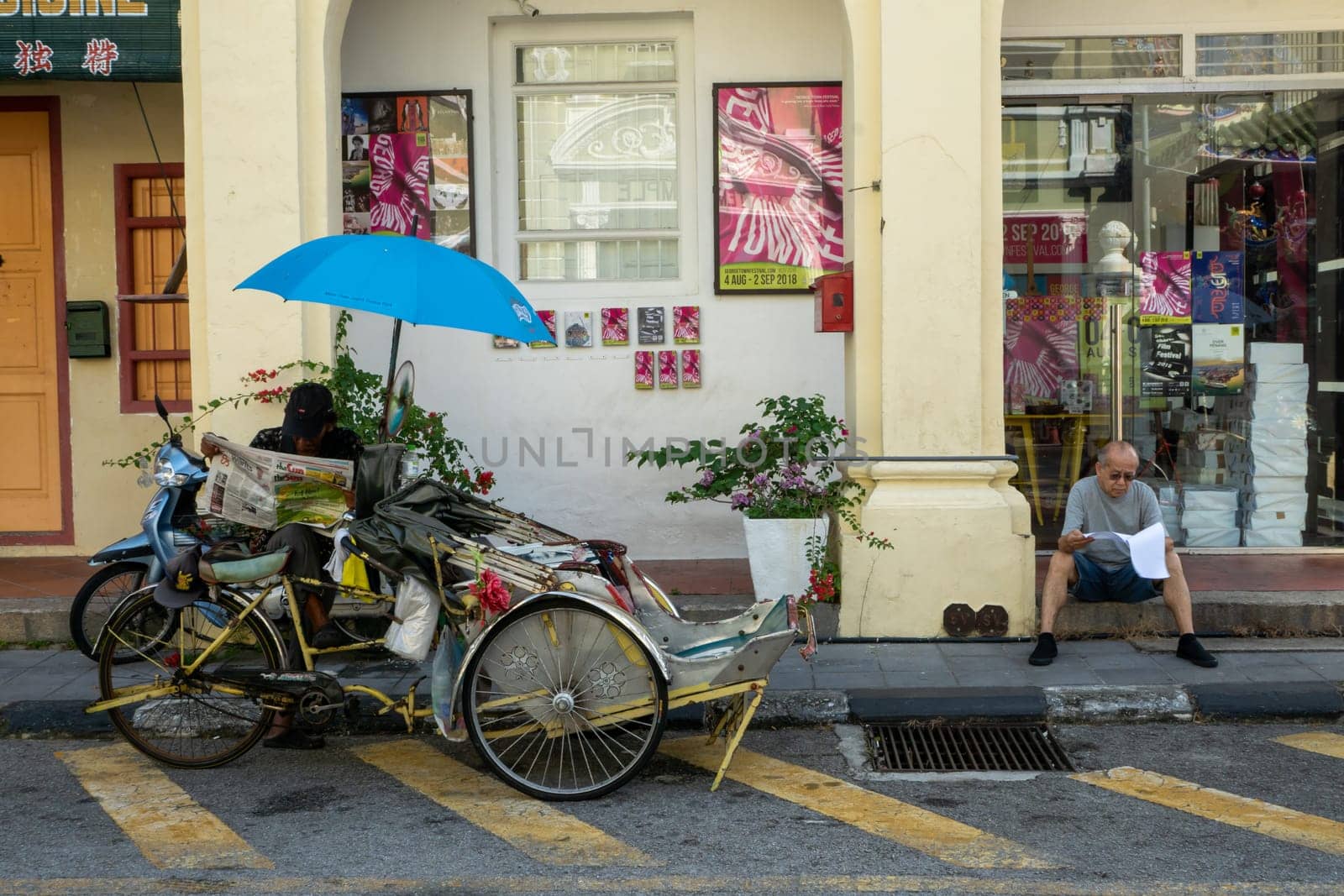 George Town, Penang/Malaysia - Jul 19 2018: Street life of Trishaw driver and people read newspaper at street.
