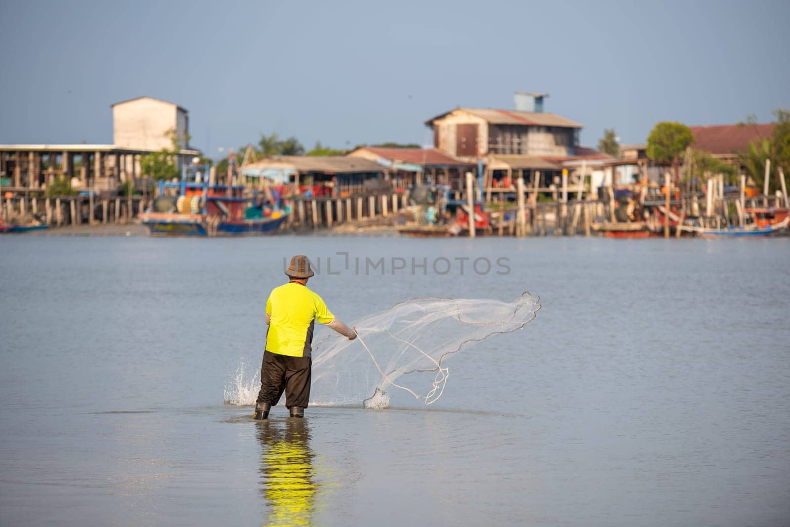 Sekinchan, Selangor/Malaysia - Oct 06 2019: A fisherman throw the net. Background is fishing village.